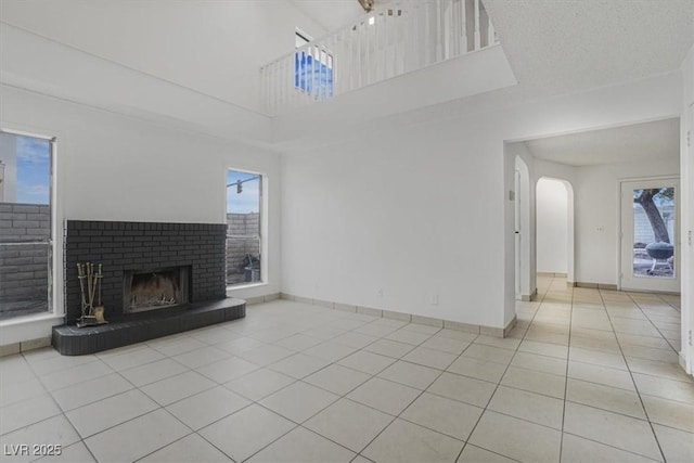 unfurnished living room featuring a fireplace, a textured ceiling, and light tile patterned flooring