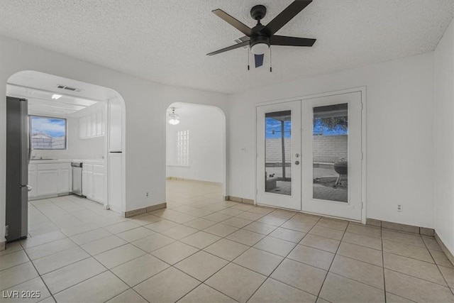 unfurnished room with ceiling fan, light tile patterned floors, a textured ceiling, and french doors