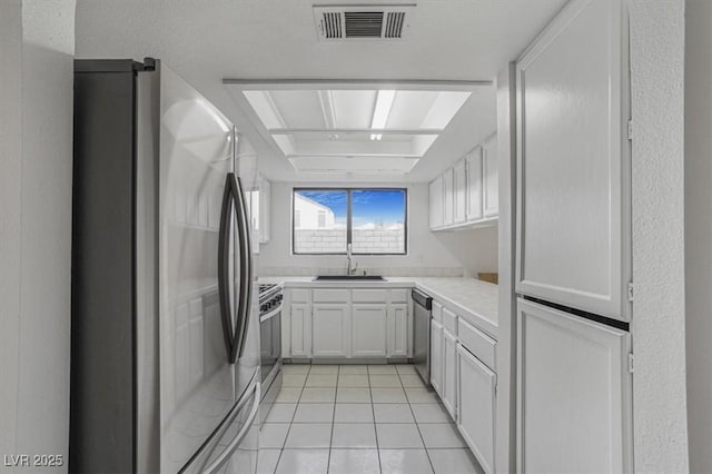 kitchen featuring stainless steel appliances, white cabinetry, sink, and light tile patterned floors