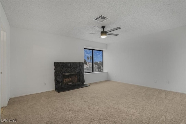 unfurnished living room featuring a stone fireplace, light colored carpet, ceiling fan, and a textured ceiling