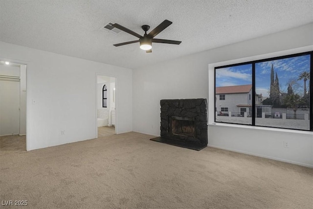 unfurnished living room with ceiling fan, a fireplace, light colored carpet, and a textured ceiling