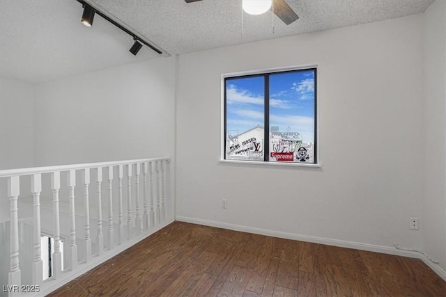 spare room featuring ceiling fan, dark hardwood / wood-style flooring, a textured ceiling, and rail lighting