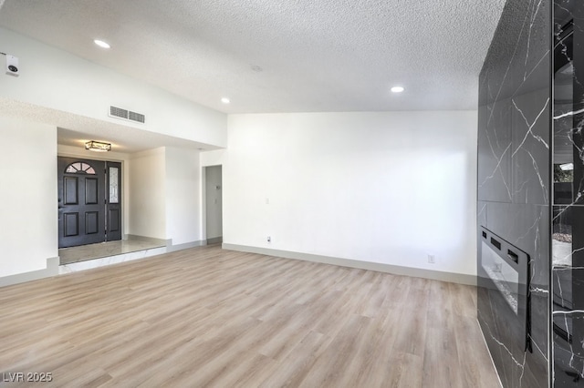 unfurnished living room featuring light hardwood / wood-style floors and a textured ceiling