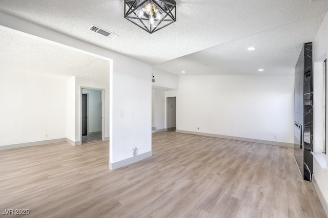 unfurnished living room with light hardwood / wood-style flooring, a chandelier, and a textured ceiling