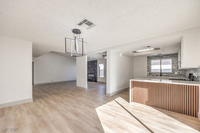 kitchen with white cabinetry, a wealth of natural light, kitchen peninsula, and pendant lighting