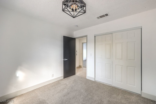 unfurnished bedroom featuring light colored carpet, a textured ceiling, and a closet