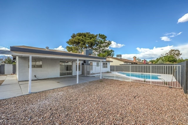 rear view of property featuring a fenced in pool and a patio