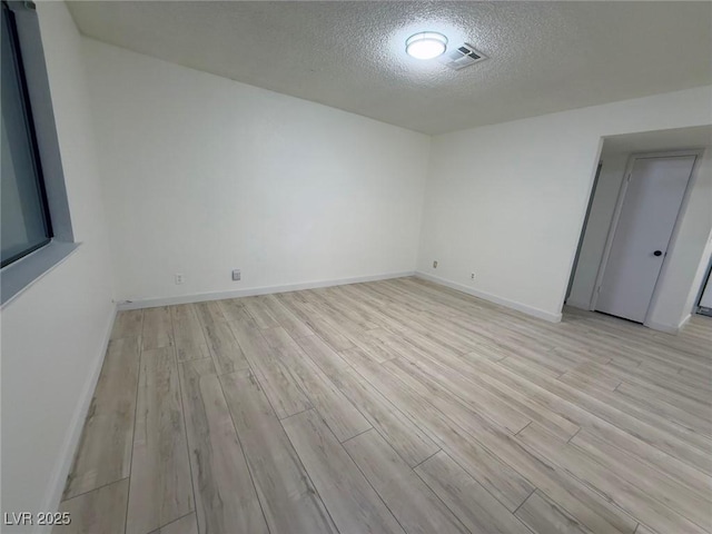 empty room with light hardwood / wood-style floors and a textured ceiling