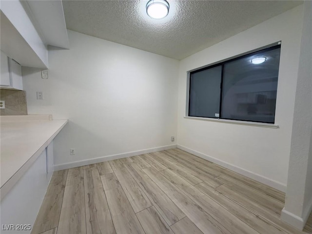 unfurnished dining area featuring light hardwood / wood-style floors and a textured ceiling