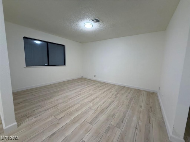 unfurnished room featuring light wood-type flooring and a textured ceiling