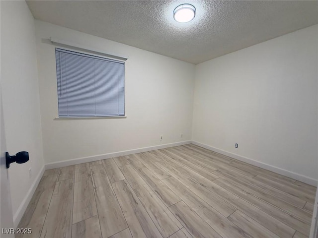 spare room with a textured ceiling and light hardwood / wood-style floors