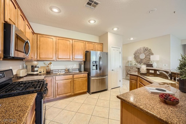 kitchen featuring dark stone countertops, sink, light tile patterned flooring, and appliances with stainless steel finishes