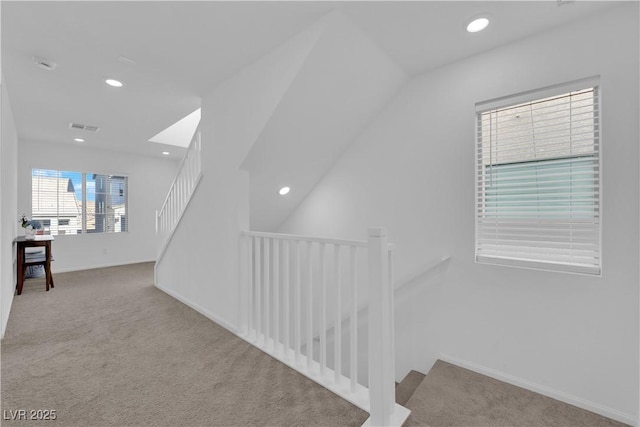 hallway with vaulted ceiling and light carpet