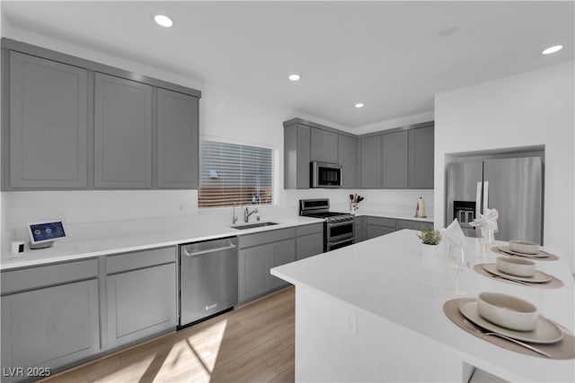 kitchen featuring light hardwood / wood-style flooring, sink, gray cabinets, and appliances with stainless steel finishes