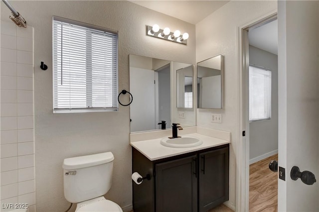 bathroom with a healthy amount of sunlight, toilet, wood-type flooring, and vanity