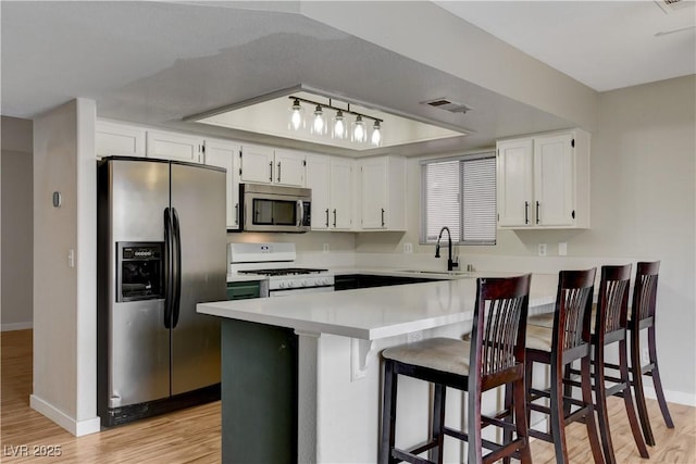 kitchen with sink, kitchen peninsula, white cabinets, and appliances with stainless steel finishes