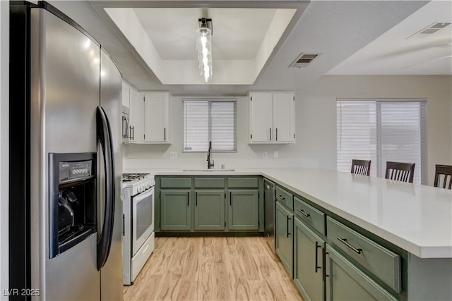 kitchen with stainless steel appliances, a tray ceiling, kitchen peninsula, and white cabinets