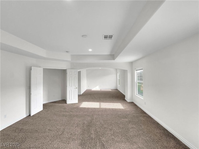 carpeted spare room featuring a tray ceiling