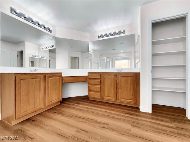 bathroom featuring hardwood / wood-style flooring, vanity, built in shelves, and walk in shower