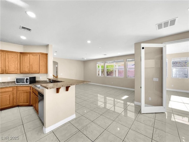 kitchen with light tile patterned flooring, sink, appliances with stainless steel finishes, a kitchen breakfast bar, and kitchen peninsula