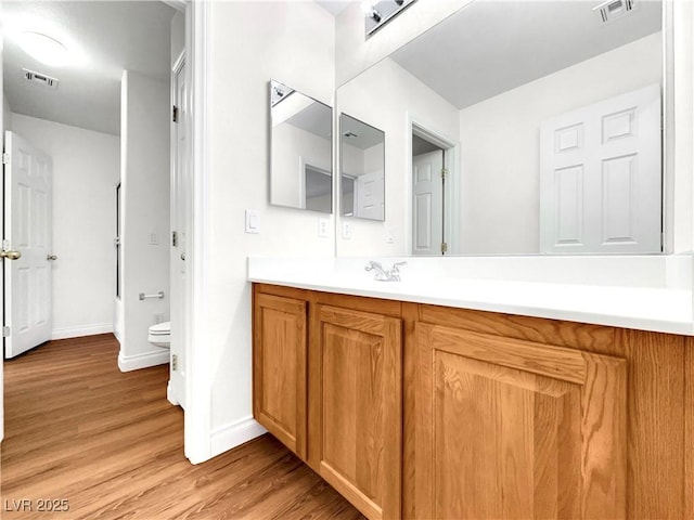 bathroom with wood-type flooring, vanity, and toilet