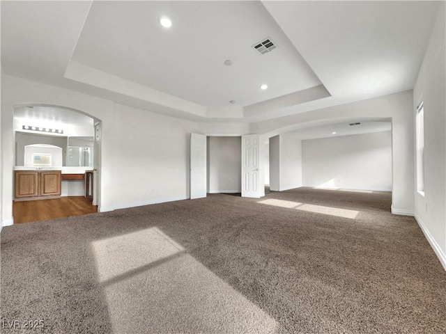 unfurnished living room with carpet and a tray ceiling