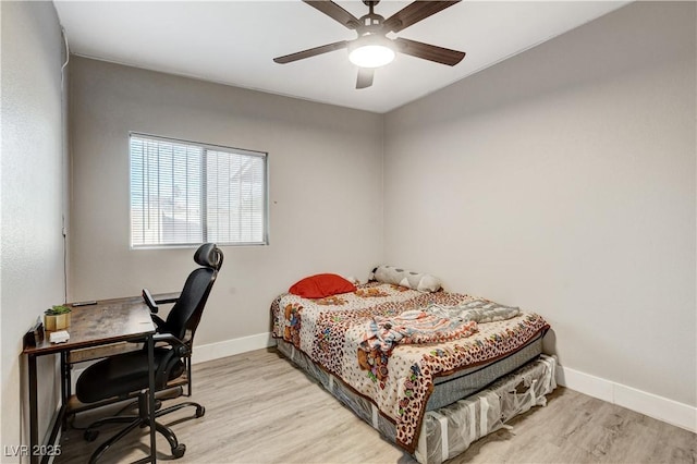 bedroom with light wood finished floors, a ceiling fan, and baseboards