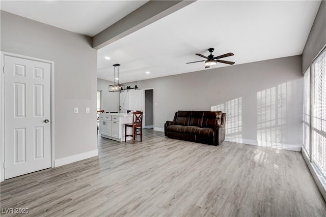 living area featuring light wood-type flooring, ceiling fan, and baseboards