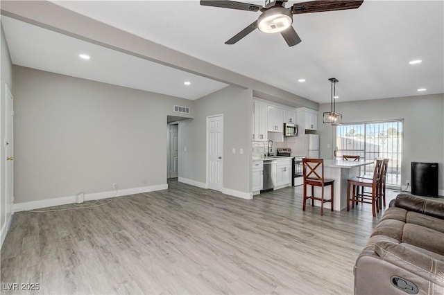 living room with recessed lighting, light wood finished floors, and baseboards