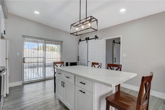 kitchen with a barn door, white cabinets, a breakfast bar, a center island, and pendant lighting