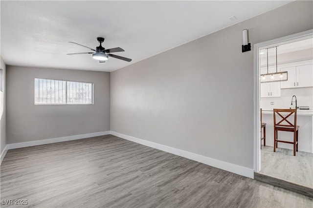 spare room featuring light wood-style floors, ceiling fan, and baseboards