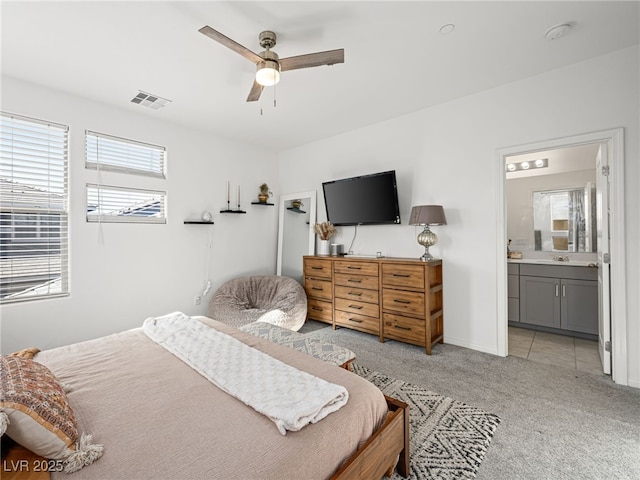 bedroom featuring ceiling fan, ensuite bathroom, sink, and light colored carpet