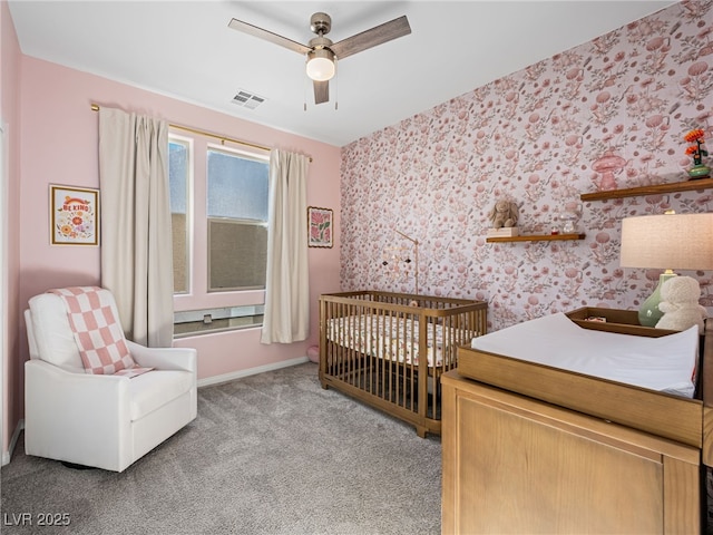 carpeted bedroom featuring a crib and ceiling fan