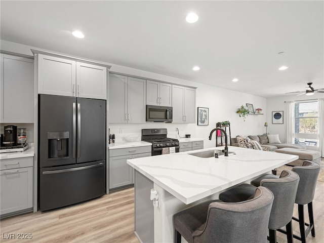 kitchen featuring an island with sink, appliances with stainless steel finishes, sink, and gray cabinetry