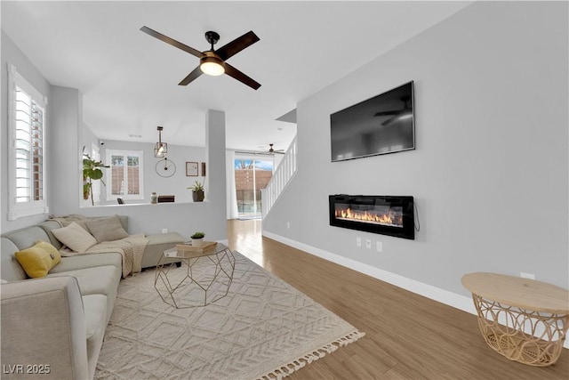 living room featuring wood-type flooring, plenty of natural light, and ceiling fan