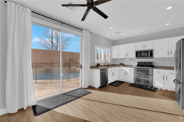 kitchen with appliances with stainless steel finishes, sink, light hardwood / wood-style flooring, and white cabinets