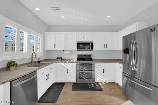 kitchen featuring white cabinetry, stainless steel appliances, sink, and light hardwood / wood-style flooring