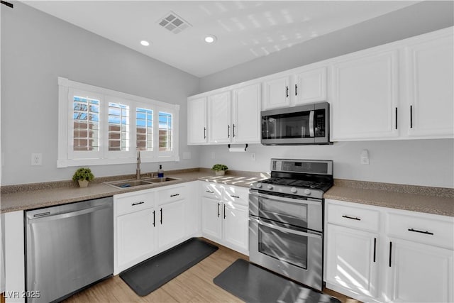 kitchen with white cabinetry, appliances with stainless steel finishes, light hardwood / wood-style floors, and sink