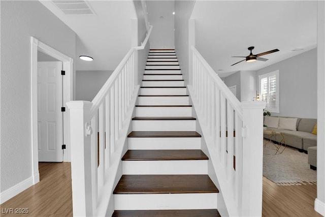 stairway with hardwood / wood-style floors and ceiling fan