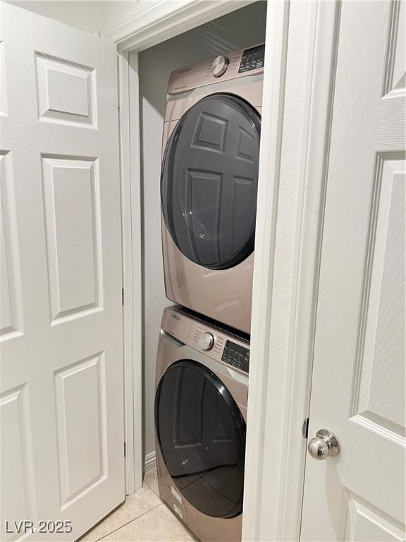 clothes washing area featuring stacked washer / drying machine and light tile patterned floors