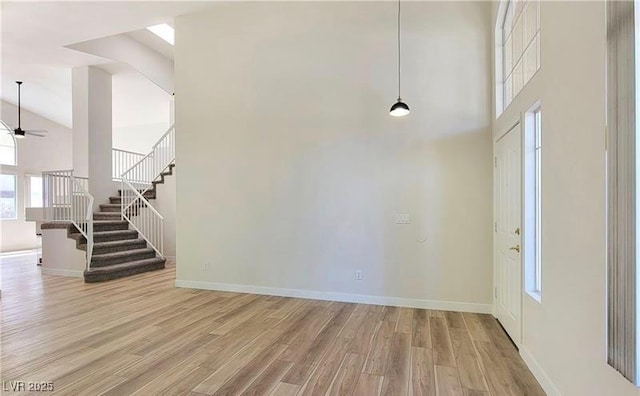 foyer entrance with ceiling fan, high vaulted ceiling, and light wood-type flooring