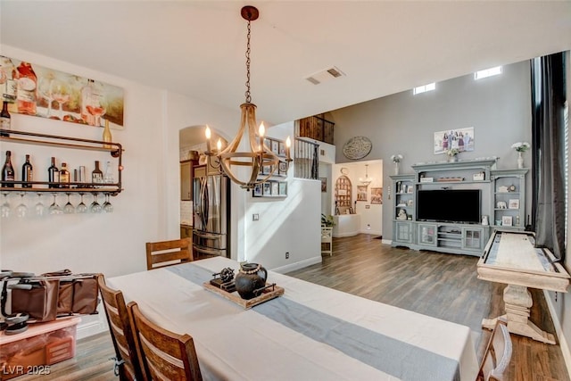 dining space featuring dark wood finished floors, visible vents, a chandelier, baseboards, and stairs