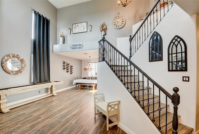 stairway featuring hardwood / wood-style flooring, a high ceiling, and a notable chandelier