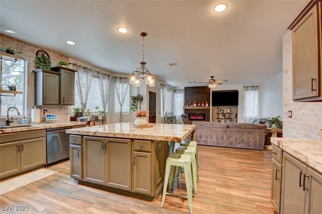 kitchen with a kitchen island, a breakfast bar, dishwasher, sink, and hanging light fixtures