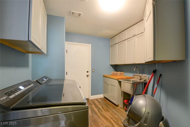 laundry area with cabinets, sink, light hardwood / wood-style floors, and washer and dryer