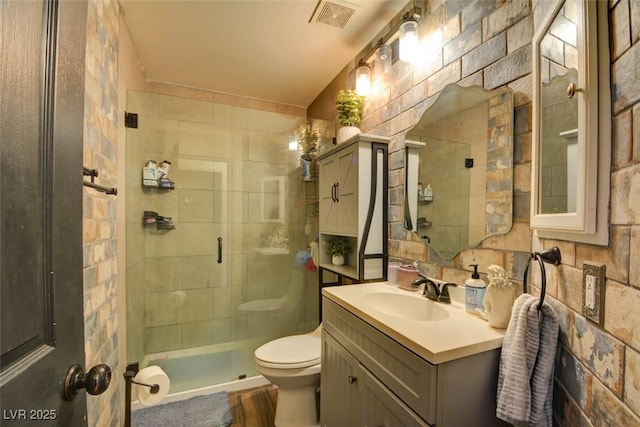 full bath featuring toilet, a stall shower, vanity, and visible vents