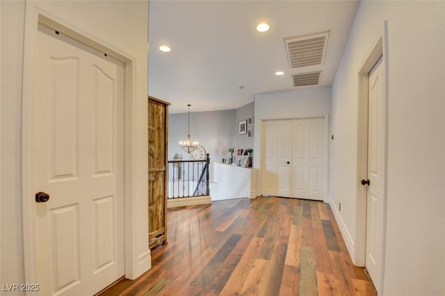 corridor featuring hardwood / wood-style floors and an inviting chandelier