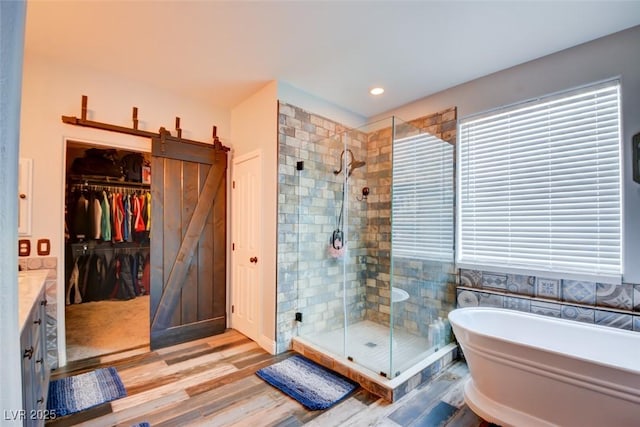 full bath featuring a freestanding tub, a shower stall, wood finished floors, and vanity