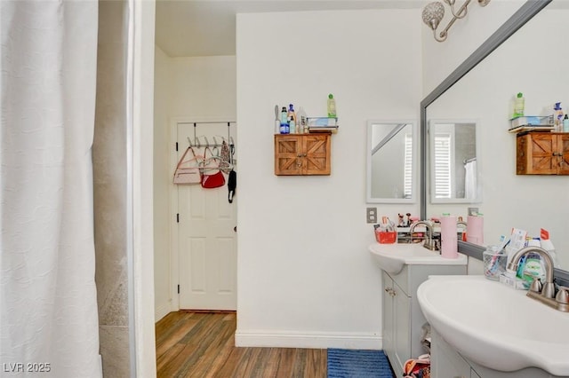 full bath featuring a shower with curtain, wood finished floors, a sink, and baseboards