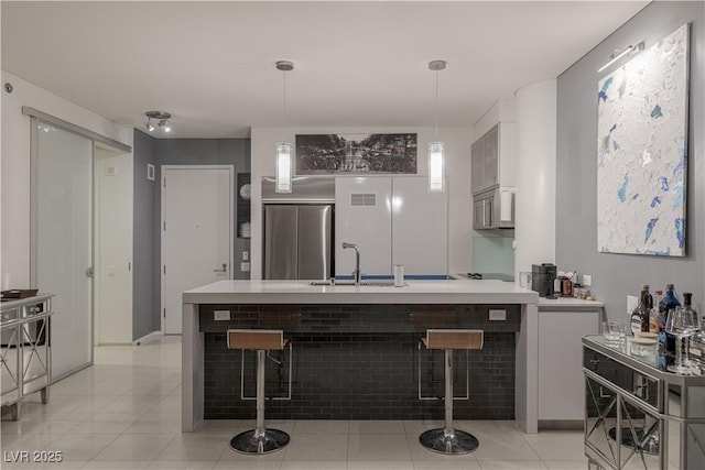 kitchen featuring pendant lighting, built in refrigerator, a breakfast bar, and sink